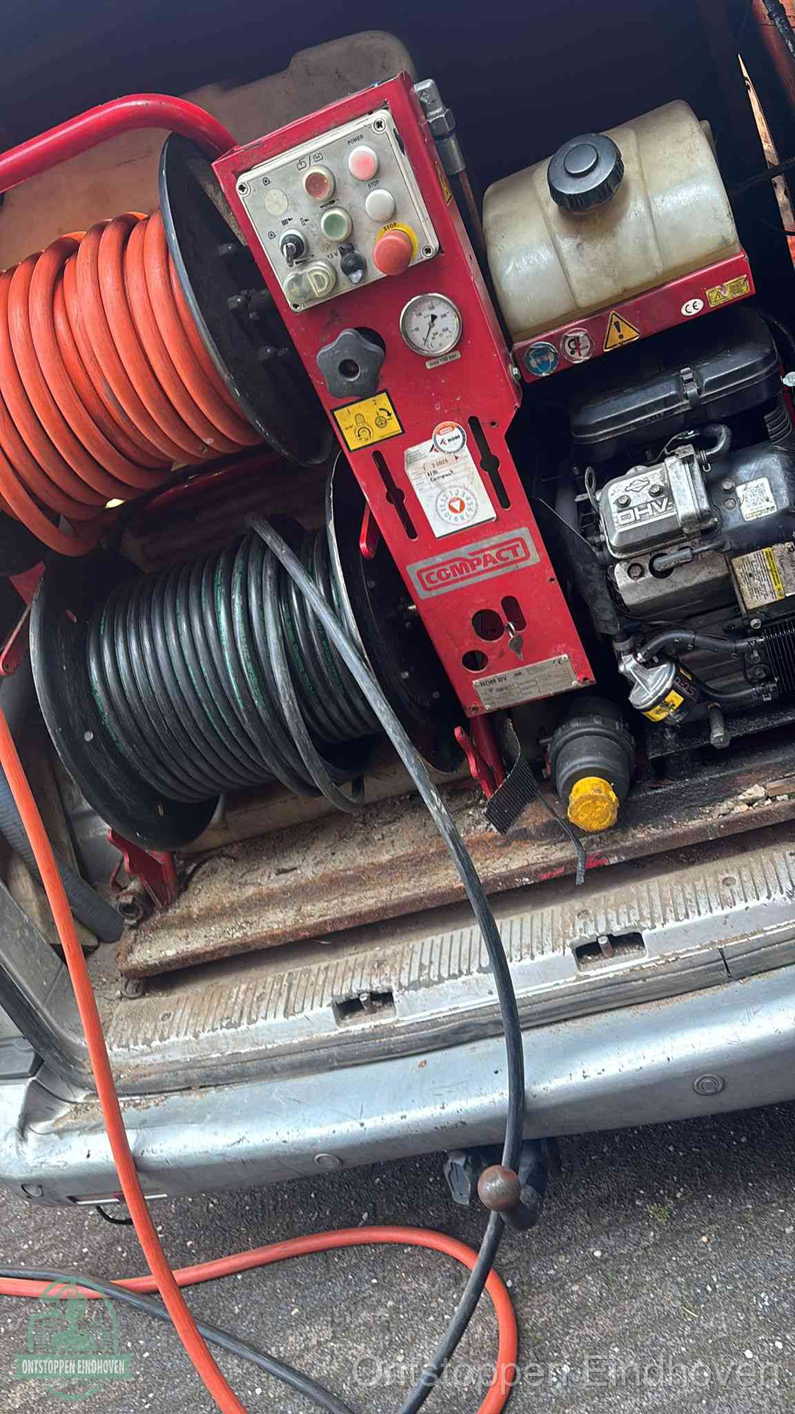Een rood hogedruk-rioolreinigingstoestel in de laadbak van de bedrijfsbus, apparatuur voor een hardnekkige afvoerverstopping in Eindhoven