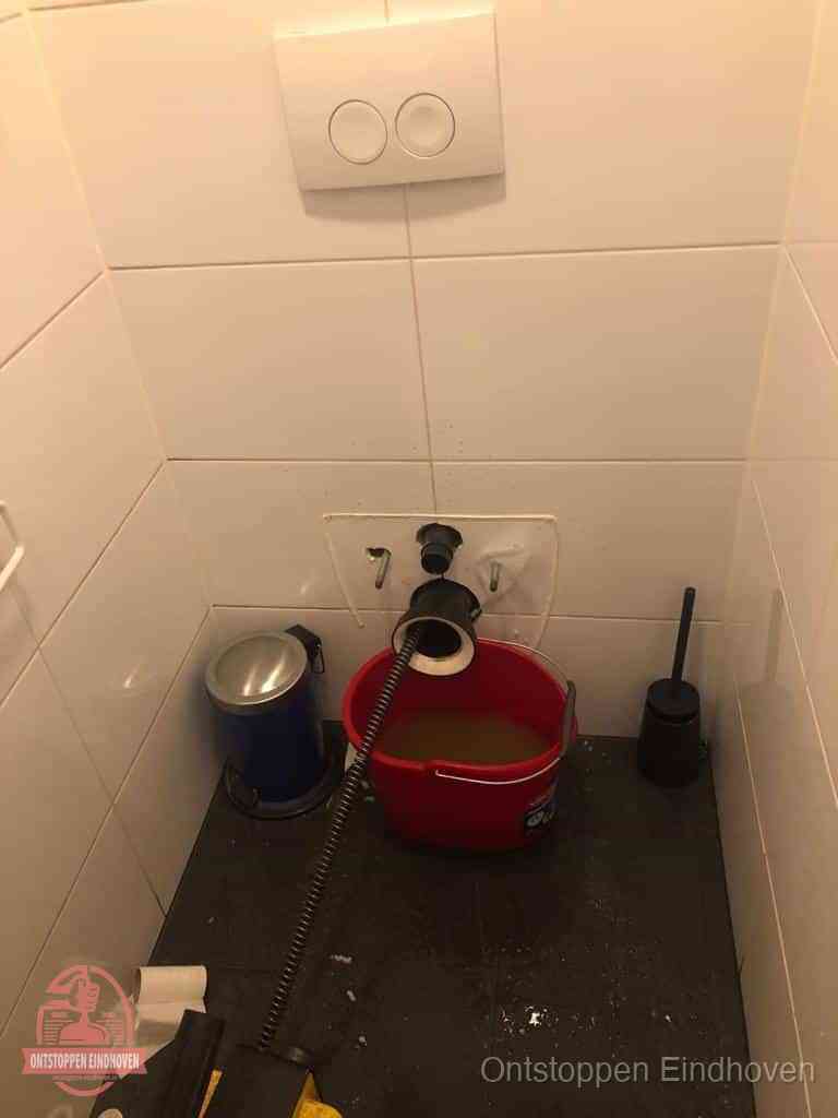 Een ontstopte wand-wc met verwijderde toiletpot waar een ontstoppingsveer in de wanduitgang verdwijnt, het achterhalen waar de verstopping zit in Eindhoven Een ontstopte wand-wc met verwijderde toiletpot waar een ontstoppingsveer in de wanduitgang verdwijnt, het achterhalen waar de verstopping zit in Eindhoven