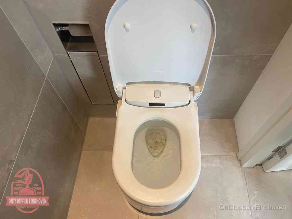 Een wit hangtoilet waarin een prop wc-papier op het water blijft drijven, een duidelijk signaal van een verstopte wc in Eindhoven