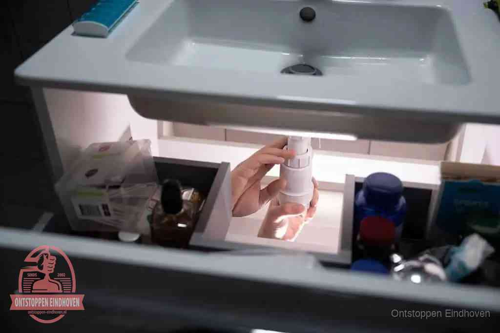 Een pompfles met zeep boven een wastafel in de toiletruimte, de warm water en afwasmiddel-methode om de wc te ontstoppen in Eindhoven Een pompfles met zeep boven een wastafel in de toiletruimte, de warm water en afwasmiddel-methode om de wc te ontstoppen in Eindhoven