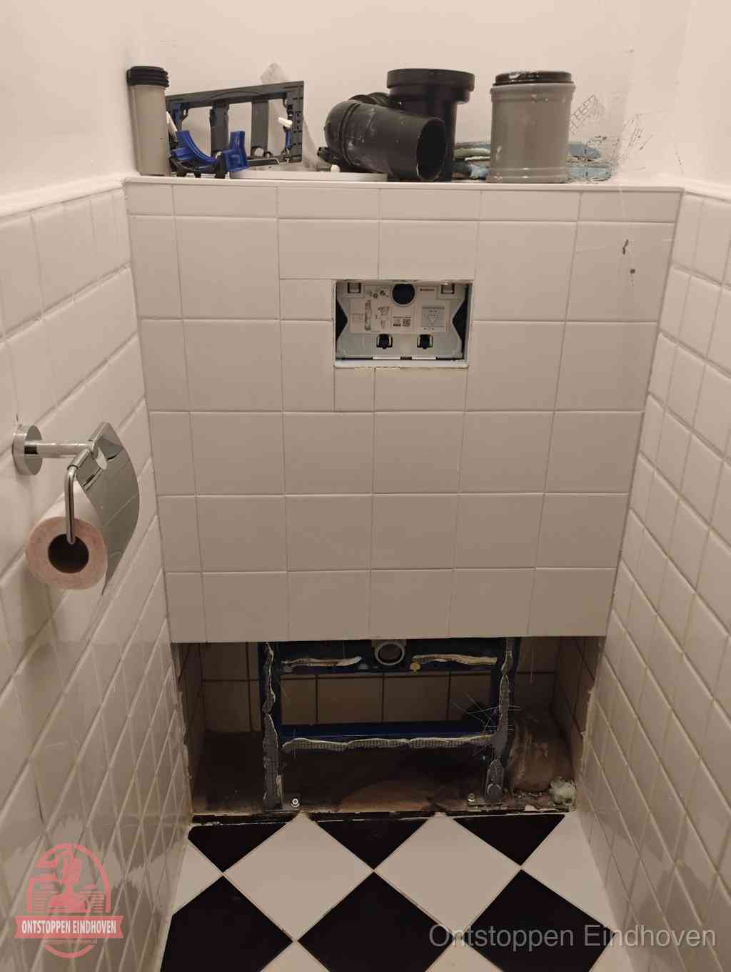 Een toiletruimte waar het hangtoilet en de inbouwreservoir-onderdelen zijn vrijgelegd voor onderhoud, periodiek nazicht voorkomt een wc-verstopping in Eindhoven Een toiletruimte waar het hangtoilet en de inbouwreservoir-onderdelen zijn vrijgelegd voor onderhoud, periodiek nazicht voorkomt een wc-verstopping in Eindhoven